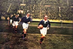 A colourised version of a black and white image showing Scotland captain Jimmy McMullan leading his team out at Wembley in 1928