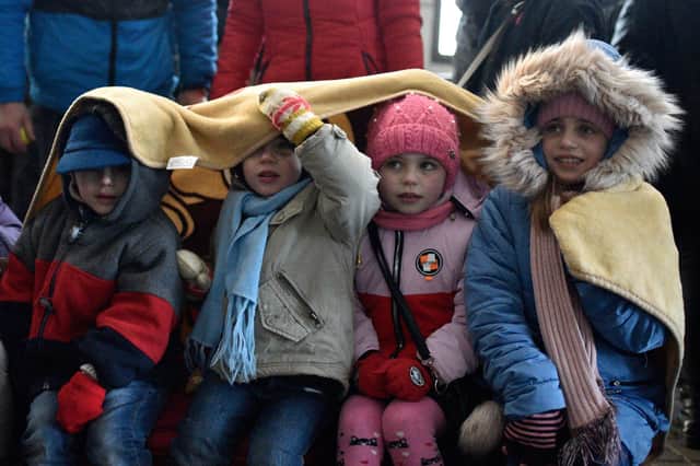 Four children share a blanket to get warm at Lviv railway station in Ukraine as people wait for evacuation trains to Poland (Picture: Ukrinform/Shutterstock)