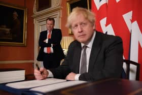 UK chief trade negotiator, David Frost looks on as  Boris Johnson signs the Brexit trade deal