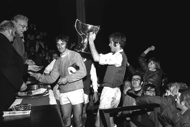 Pat Stanton prepares to lift the League Cup trophy as goalkeeper Jim Herriott, foreground, accepts his medal