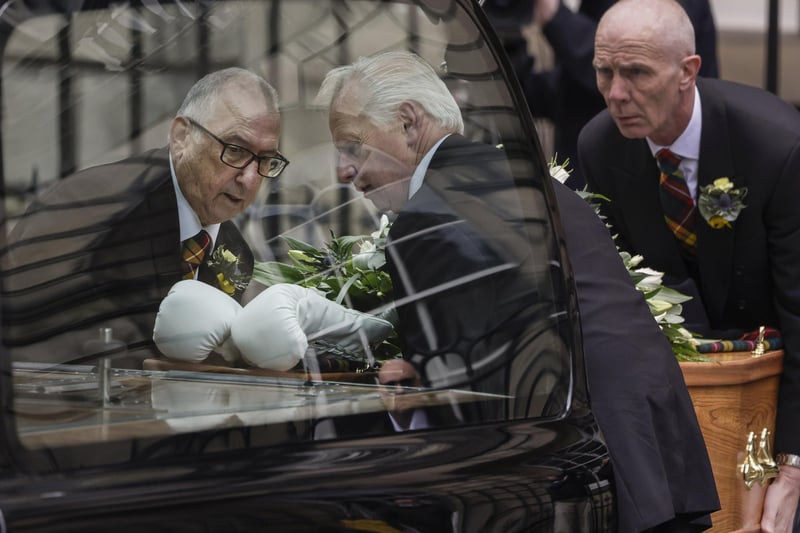 White boxing gloves lie on the coffin as it carried into a hearse to leave the ceremony