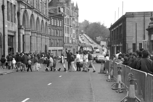 The queue for the Dinosaurs Alive! exhibition at the City Art Centre Edinburgh snaked up Market Street and across the road in February 1990. A policeman holds up the traffic to let people cross.