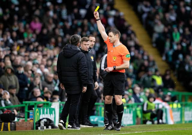 Referee Steven McLean shows the yellow card to Hibs boss Lee Johnson