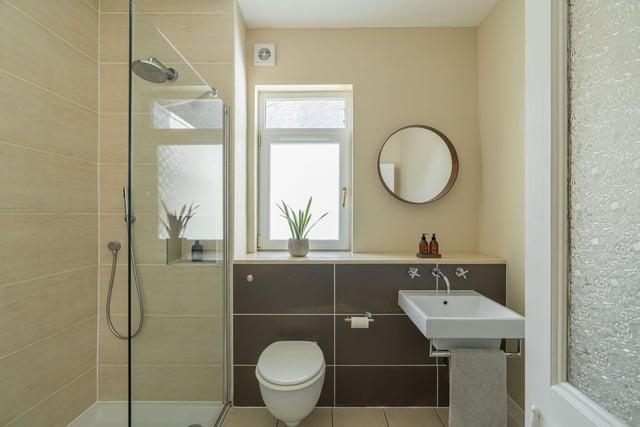 The convenient downstairs shower room with two-piece white modern suite, tiling to floor/splash areas and a walk-in enclosure with drench shower.