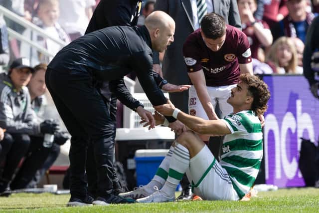 Celtic's Jota is helped to his feet by Hearts interim manager Steven Naismith after a collision.