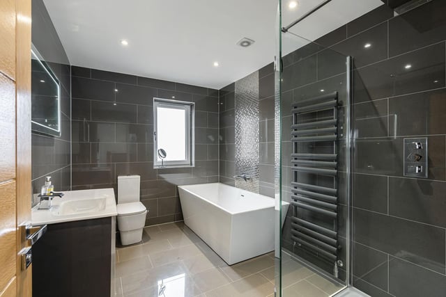 The spacious family bathroom with contemporary three piece white suite, contrasting tiling and walk-in drench shower.