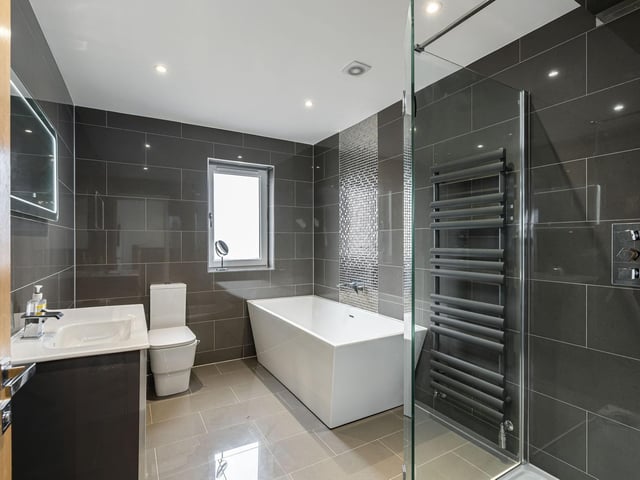 The spacious family bathroom with contemporary three piece white suite, contrasting tiling and walk-in drench shower.