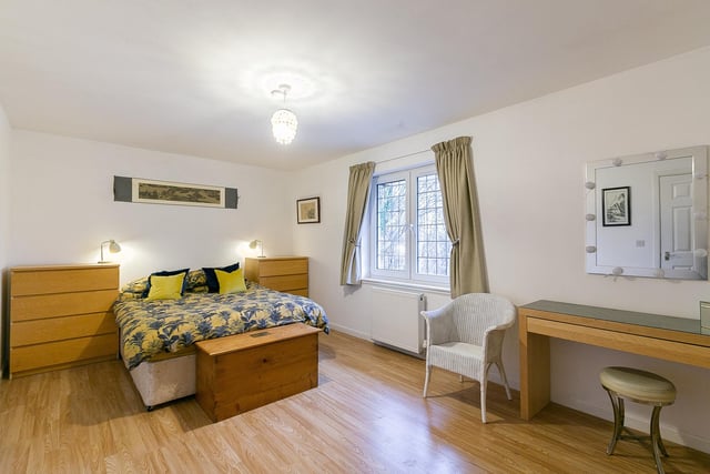 The spacious master bedroom is set to the rear with wood effect flooring, a built-in wardrobe, a central light fitting and a modern en-suite shower room with a mains mixer shower, tiled splash walls and a ladder-style radiator.