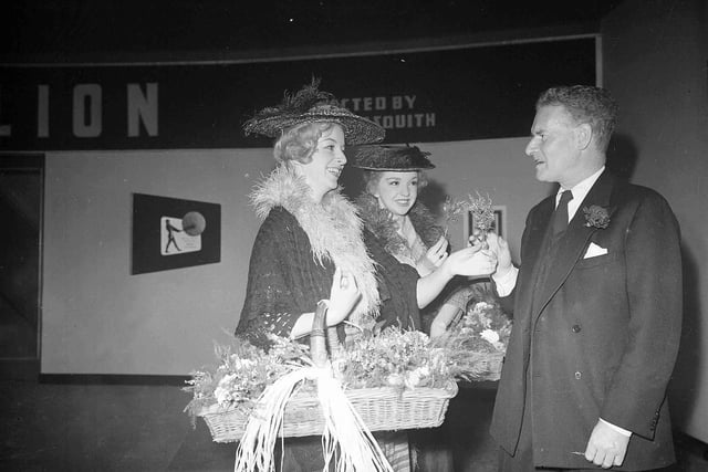 Anthony Asquith receives heather from Susan Parar and Elizabeth 'Pygmalion' Griffith at the Rank Organisation's 21st birthday celebration in the New Victoria Cinema during the festival in 1956.