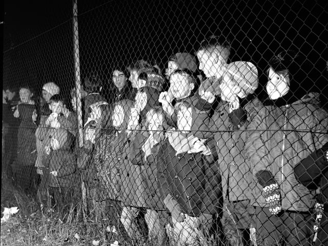 Children are kept safe behind a chain link fence at an organised bonfire and firework show staged at Redford Barracks in Edinburgh in November 1968