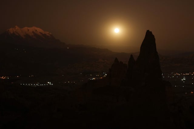 The full moon rises beside the snow capped Illimani Mountain, on the outskirts of La Paz, Bolivia, Tuesday, June 14, 2022. (AP Photo/Juan Karita)