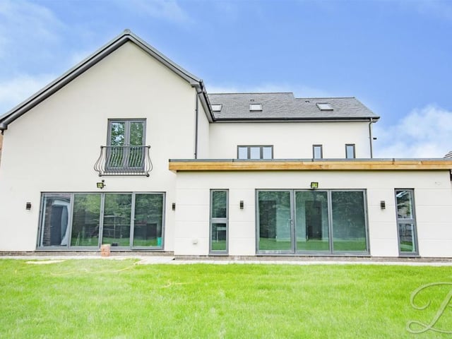 A view from the back of the house, where there is a spacious garden with a well-maintained lawn.