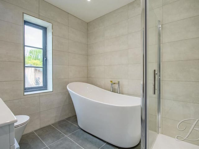 The en suite to the third bedroom in the house. It features a free-standing bath and a walk-in-shower, plus vanity unit and low-flush WC.
