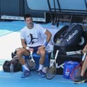Defending champion Novak Djokovic, left, talks with a teammate during a practice session in the Rod Laver Arena in Melbourne