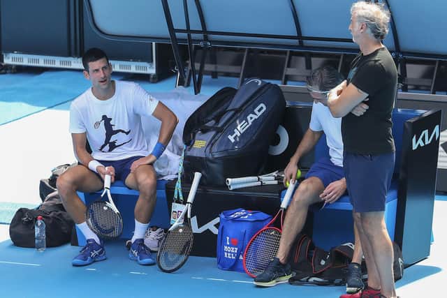 Defending champion Novak Djokovic, left, talks with a teammate during a practice session in the Rod Laver Arena in Melbourne