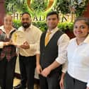 Mr Khan, pictured centre in group of five with Radhuni front of house staff,