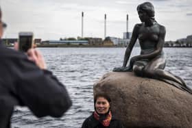 Tourists photograph themselves with the famous Little Mermaid statue at the harbour in Copenhagen (Picture: Odd Andersen/AFP via Getty Images)