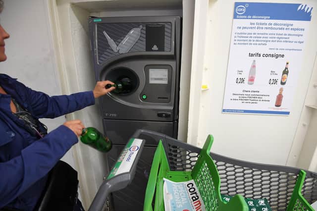A customer deposits empty returnable glass bottles into a device at a hypermarket in France