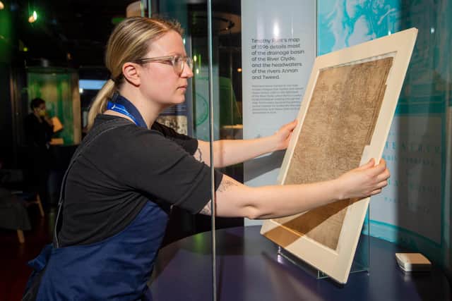 Library conservator Lizzie Fuller installs a 16th century Timothy Pont map detailing most of the drainage basin of the River Clyde. Credit: Neil Hanna