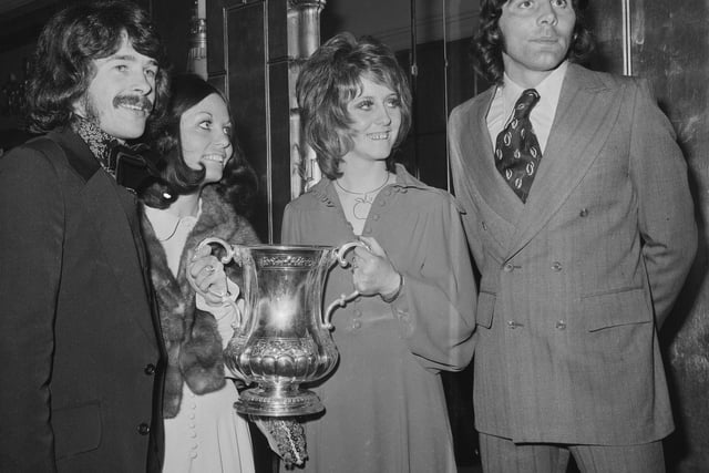 Ian Porterfield and Bobby Kerrcelebrate winning the FA Cup with their wives, who are holding the trophy.