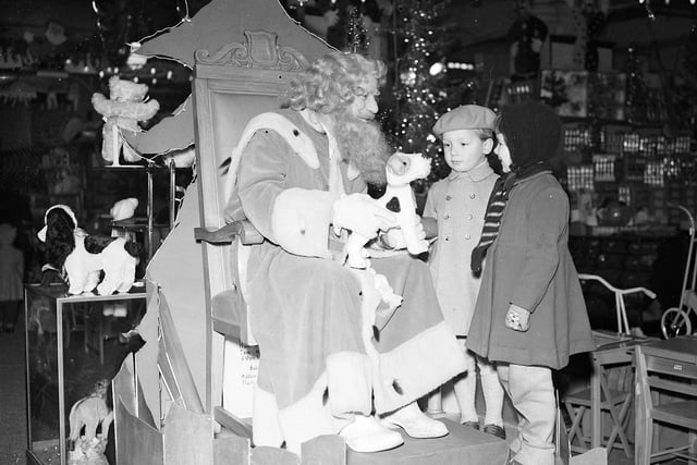 Two children meet Santa Claus at his grotto in Jenners.