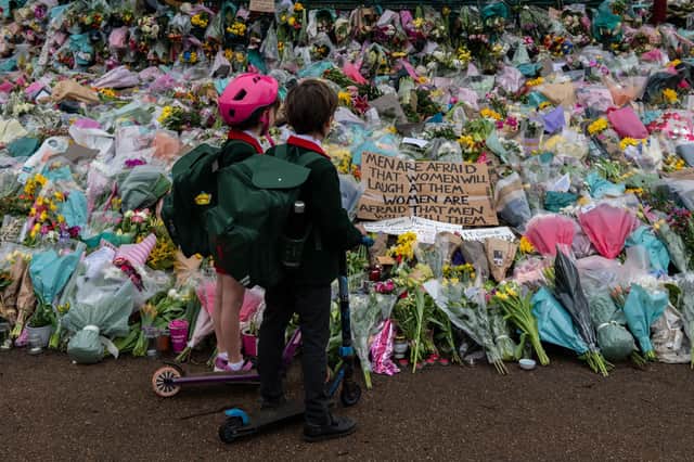 Two school children stop to look at floral tributes left at Clapham Common bandstand in memory of Sarah Everard, who was murdered by a serving police officer (Picture: Chris J Ratcliffe/Getty Images)