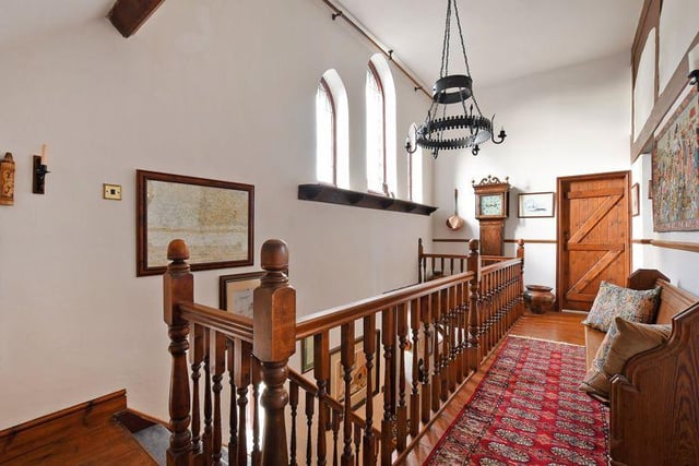 Here's a look at the galleried landing, where a cast iron light fitting hangs and a pew has been positioned.
