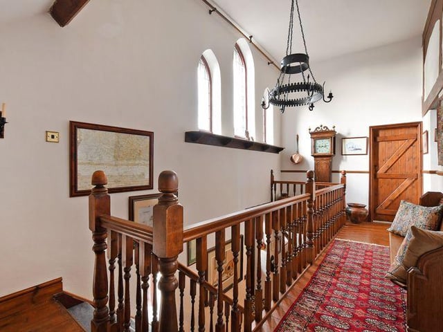 Here's a look at the galleried landing, where a cast iron light fitting hangs and a pew has been positioned.