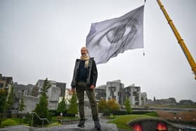 The massive We Are Watching artwork has been hoisted near the Scottish Parliament in Edinburgh as part of a tour that will see it flying in Glasgow during the United Nations climate summit COP26