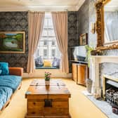 The bright and airy lounge with custom-built window seating, beautiful cornicing, an Edinburgh press cupboard and a feature gas fireplace,