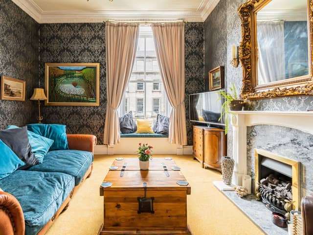 The bright and airy lounge with custom-built window seating, beautiful cornicing, an Edinburgh press cupboard and a feature gas fireplace,