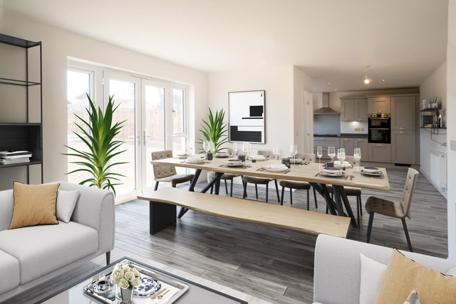 The kitchen is fully equipped with modern amenities, including a five-burner gas hob, double oven, integrated fridge freezer, and dishwasher. The open plan kitchen leads into the dining room and family area which spans the whole width of the house