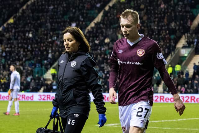 Hearts winger Lewis Moore and physio Karen Gibson walking round the pitch at Easter Road