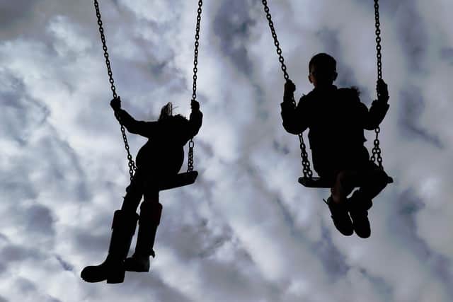 File photo of children playing on swings in a park.