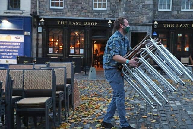 A man stacking away chairs outside The last Drop pub in The Grassmarket, Edinburgh.