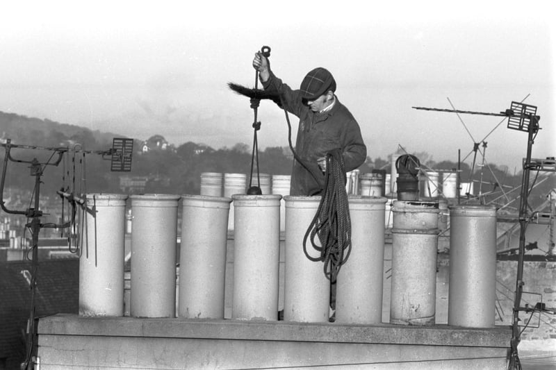 Chimney sweep Mike McLenaghan at work in Edinburgh, November 1981. Mike lowers the brush down a chimney.