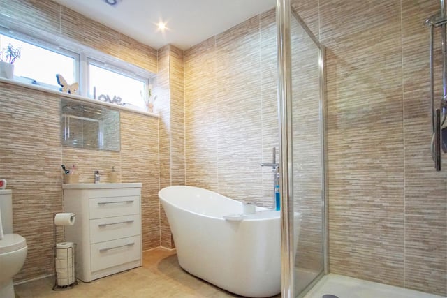 The spacious ground floor bathroom features modern white sanitary ware including a freestanding traditional slipper bath to complement the separate shower compartment with its rainfall shower head and handset. There is tiling all round, storage capacity beneath the basin and a chrome, heated towel ladder.