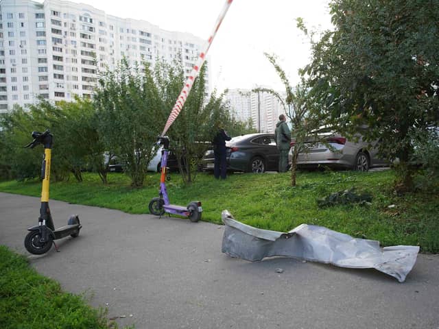 Local residents stand next to debris following thet drone attack in Moscow