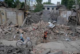 A local resident pushes her bicycle through damaged buildings in Toretsk, eastern Ukraine, in August last year (Picture: Bulent Kilic/AFP via Getty Images)