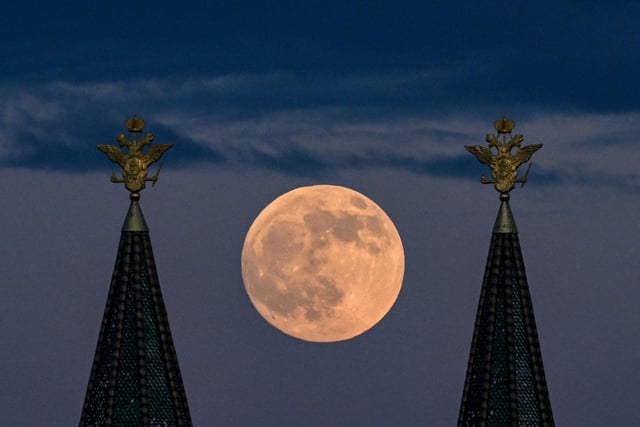The full moon also known as Flower blood moon is pictured behind the two-headed eagle, the national symbol of Russia atop a building on Red Square in downtown Moscow  (Photo by KIRILL KUDRYAVTSEV/AFP via Getty Images)