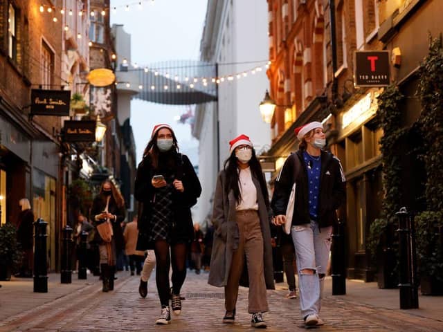Pedestrians, some wearing face coverings to combat the spread of Covid-19, walk past shops in Covent Garden on the last Saturday for shopping before Christmas, in central London on December 18, 2021. Photo by TOLGA AKMEN/AFP via Getty Images