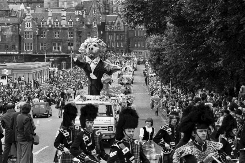 A pipe band leads a giant papier mache lion conductor in the Evening News Edinburgh Festival Cavalcade, August 1980.