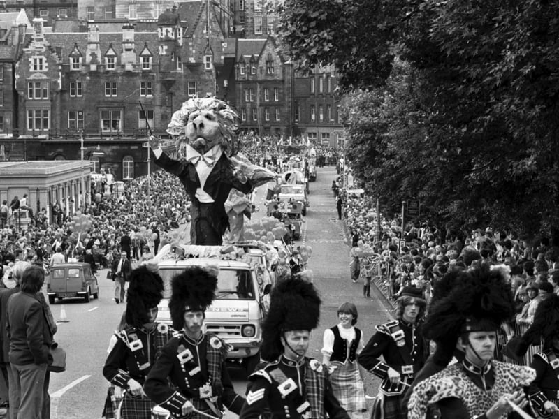 A pipe band leads a giant papier mache lion conductor in the Evening News Edinburgh Festival Cavalcade, August 1980.