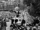 A pipe band leads a giant papier mache lion conductor in the Evening News Edinburgh Festival Cavalcade, August 1980.