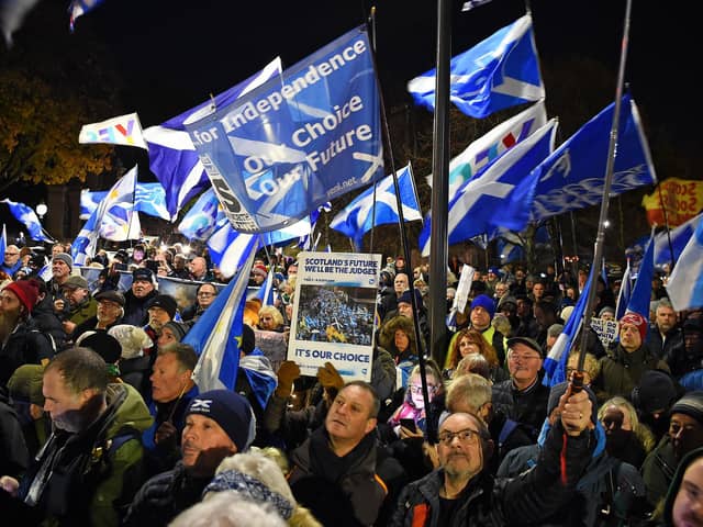 Independence supporters wave Saltire flags during a rally outside the Scottish Parliament following the announcement of the Supreme Court's ruling