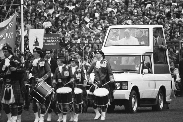 Pope John Paul II enters Edinburgh's Murrayfield rugby stadium in the 'Popemobile', led by a pipe band.