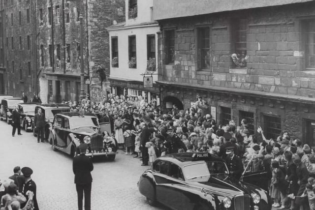 The new Queen visited Huntly House Museum on the Royal Mile on June 28, 1952. 
A large crowd gathered on either side of the street in the Canongate to catch a glimpse of her. A row of polished black cars are parked outside the building which now houses the Museum of Edinburgh. The young Queen can be seen wearing a hat and a fur wrap over her dress as she talks to an official beside the open door to her awaiting car.