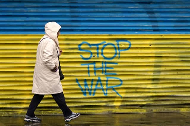 A woman walks past anti-war graffiti in support of Ukraine, painted on shutters in Dublin city centre. Photo: Niall Carson/PA Wire.