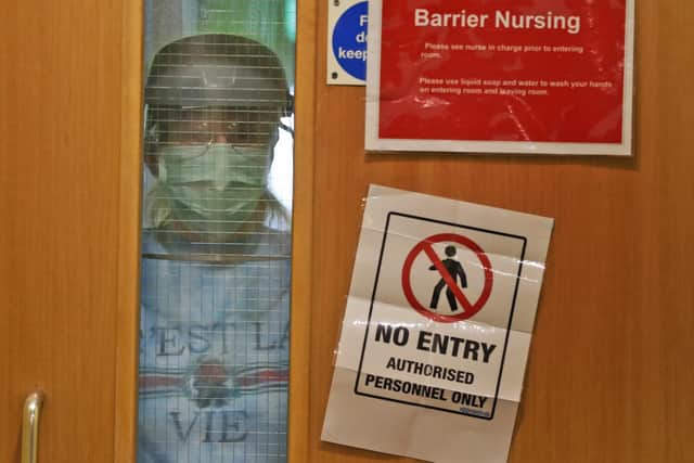 A nurse wearing PPE looks through a window of a door lead to a segregated part of a care home as the Covid pandemic raged in April 2020 (Picture: Frank Augstein, AP)