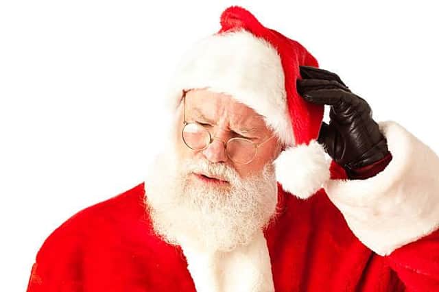 Head and shoulders close-up of Santa Claus in a perplexed, thinking, pensive, or forgetful expression. He is wrinkling his face with his hand touching his head struggling to remember. photographed on white background in horizontal format with copy space available.